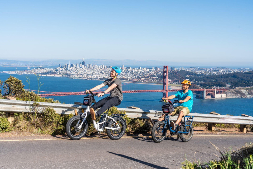 Two riders at a scenic overlook above the bay