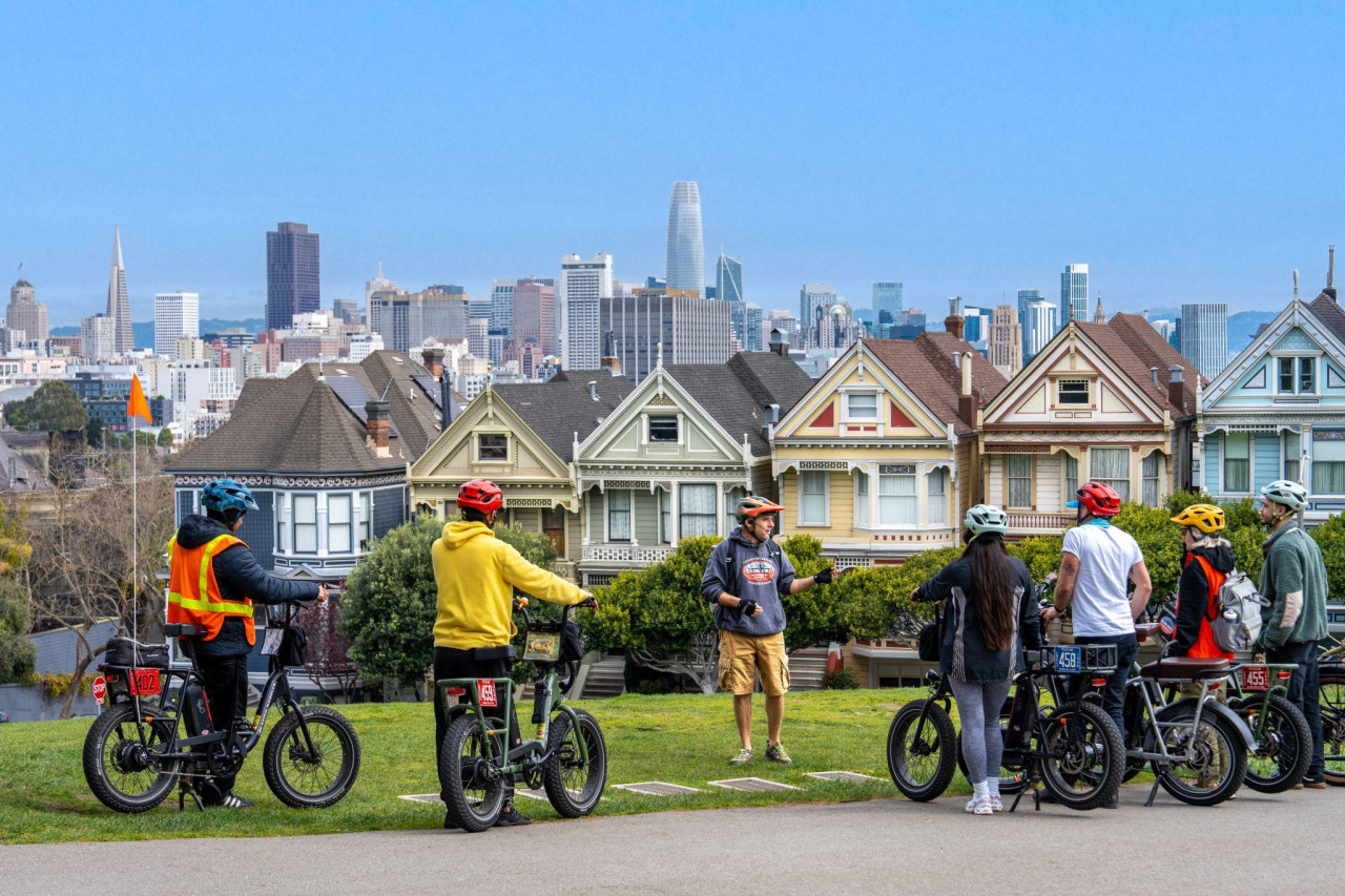 Family riders paused together with bridge and skyline views