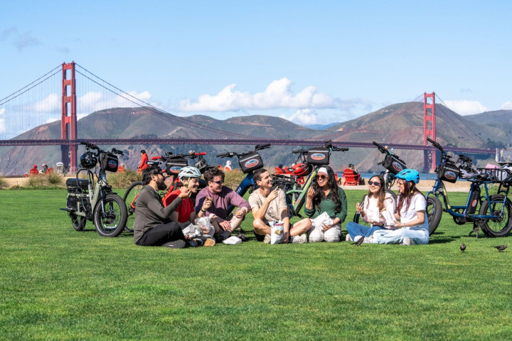 Family bike group on a lawn near the Golden Gate Bridge