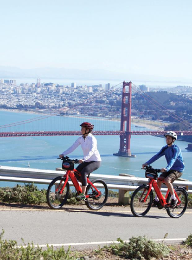 Couple riding electric bikes in the Marin Headlands with breathtaking views of San Francisco and the Golden Gate Bridge