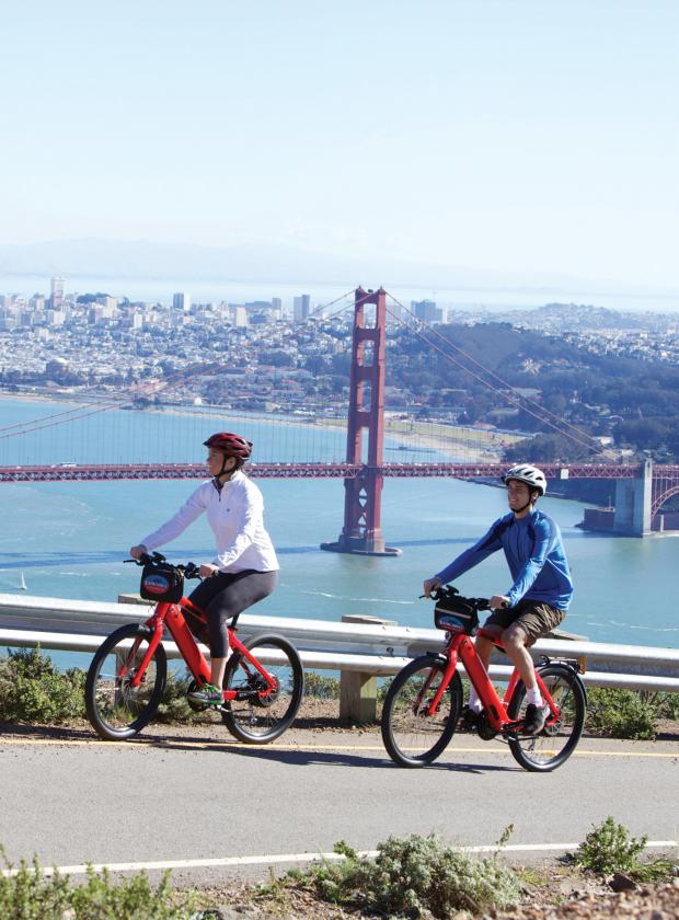 Couple of bikers on Hawk Hill in the Marin Headlands with stunning views of the Golden Gate Bridge and San Francisco